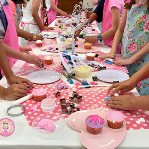 girls decorating cupcakes at a kids party with We Came Here to Party